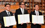 協定書を掲げる安芸社長（中央）と広田市長（左）、平井知事＝８日、東京都千代田区のグッドスマイルカンパニー本社