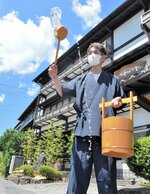 青空の下で打ち水をまく岩井屋のスタッフ＝２２日、鳥取県岩美町岩井