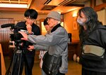 撮影方法について話し合うスタッフらを見守る荒尾さん（右）＝８日、鳥取市気高町浜村