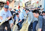 【力の限り】力いっぱい綱を引く参加者。上組が３０センチほど自陣に引き寄せ、勝利を収めた