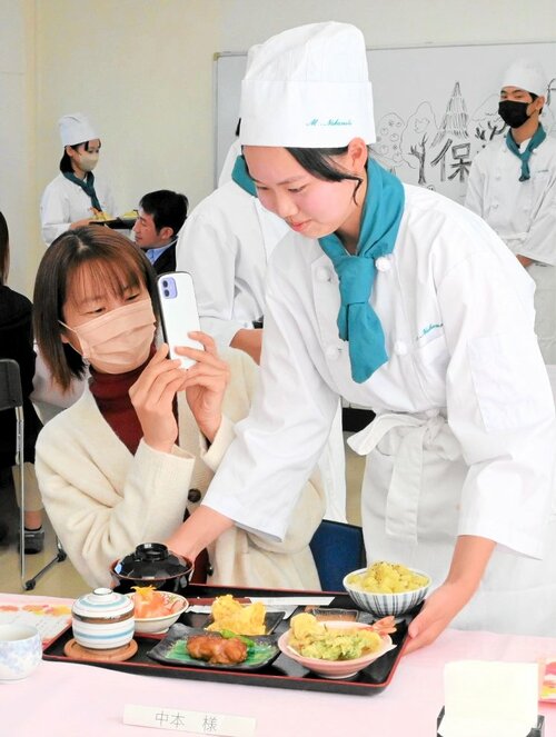 心を込めて作った和定食を保護者へ配膳する生徒