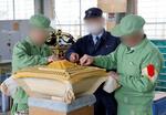 　作業専門官（中央）の助言を受けて、みこしの屋根の塗装前作業をする受刑者＝２０２４年１２月、富山市（画像の一部を加工しています）