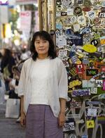 　東京・渋谷の道玄坂で、チラシが貼られた電話ボックス脇の川添愛さん＝２０２４年１０月（撮影・林昌三）