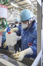 　２月、東京電力福島第１原発構内で処理水を採取する中国の分析機関の担当者（東電提供）