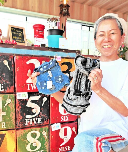 来店客から寄せられたぺット服を手にする田中さん＝三朝町大柿のドッグカフェＲＩＫＵとＭＵＧＩ