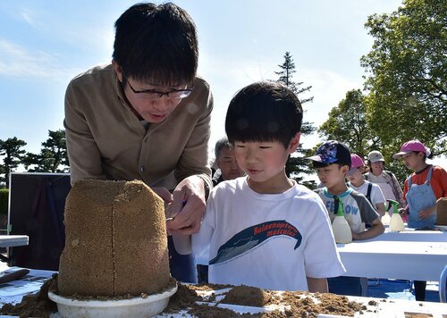 ツタンカーメンの砂像に挑戦する親子連れ＝１３日、鳥取市東町２丁目の県立博物館