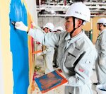 こてを使って壁を塗る体験をする生徒＝１４日、倉吉市駄経寺町２丁目の鳥取県立美術館建設現場