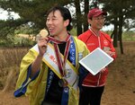 鳥取砂丘ルートでゲームを体験し、特製の金メダルを掲げる入江さん（左）＝２１日、鳥取市の鳥取砂丘