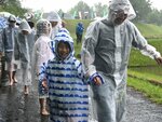 あいにくの雨の中でも、雨がっぱを着て笑顔で田植えに向かう親子