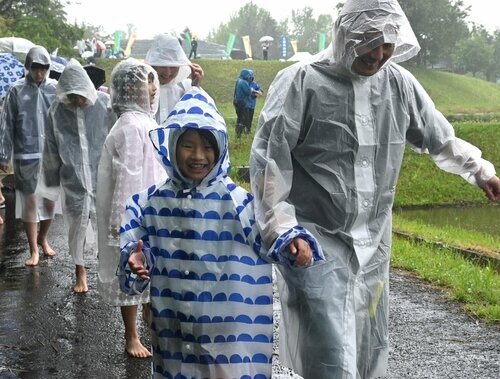 あいにくの雨の中でも、雨がっぱを着て笑顔で田植えに向かう親子