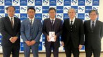 太田社長（左から２人目）から贈られた目録を手にする原田学長（中央）