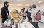 湯飲みを手に取り品定めする来場者＝１７日、鳥取市富安２丁目の日本海新聞ビル５階ホール