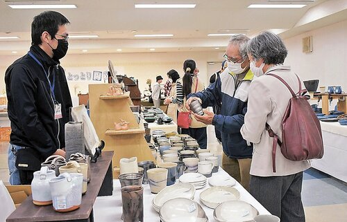 湯飲みを手に取り品定めする来場者＝１７日、鳥取市富安２丁目の日本海新聞ビル５階ホール