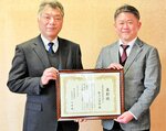 本紙を活用したＮＩＥ活動が評価されて表彰を受けた久米校長（左）と河原教育長＝４日、琴浦町のまなびタウンとうはく