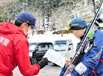 スキー客（右）にチラシを手渡して注意を呼びかける署員＝３０日、香美町小代区大谷のおじろスキー場