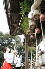 背丈以上ある長いササを使い、軒下にたまったほこりを払う文佳さん（左）と直弥さん＝２８日、倉吉市八幡町の倉吉八幡宮