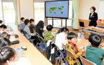 とっとりＳＤＧｓ伝道師の洋谷さん（右奥）の話を真剣に聞く児童ら＝１５日、米子市博労町４丁目の啓成小