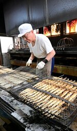 背後のガスバーナーで焼いたニギスをいったん休め、裏返す作業＝香美町香住区香住の浜貞商店