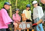 地元有志と山頂までの到達目安が書かれた案内看板を設置する児童