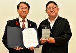 平井知事（左）からおもてなし大使の委嘱を受けた「かに吉」の山田オーナー＝８日、鳥取市のとりぎん文化会館