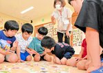 豊岡の伝統野菜や郷土料理などの文章が読み上げられるのを聞き、絵札を探す園児たち＝２１日、豊岡市日高町中の八代保育園