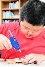 木の台座を装飾してキーホルダーを作る児童