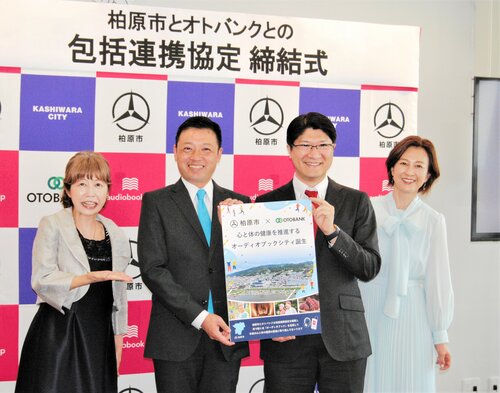 調印を終え、記念撮影に応じる（左から）ＴＡＲＡＫＯさん、冨宅市長、上田会長、森尾さん