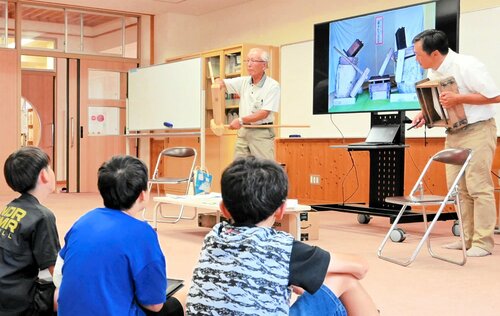 堤さん（中央）から見立ての技を教わる児童たち