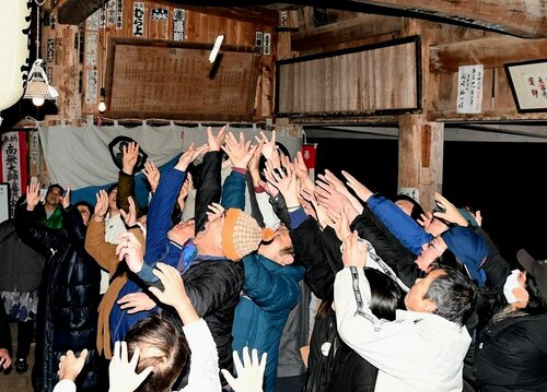 投下された福木を求め、懸命に手を伸ばす参拝者ら＝１５日夜、鳥取県倉吉市仲ノ町の長谷寺