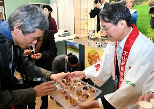 来場者にたこ焼き風シュークリームを振る舞う平井知事（右）＝１３日、大阪市此花区の夢洲
