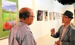来館者に自身の描いたモチーフや画法を説明する岡部さん（右）＝３日、新温泉町の浜坂先人記念館・以命亭