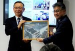 運用を開始した太陽光発電設備の写真を寄贈されるササヤマの笹山社長（右）＝２５日、鳥取市河原町布袋