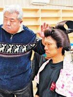 真剣な表情でかつら合わせをする役者