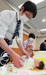 沐浴の後、赤ちゃんの人形に服を着せる職員＝１月３１日、鳥取市東町１丁目の県警本部