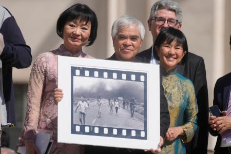　「ナパーム弾の少女」として知られる写真を持つニック・ウット氏（中央）＝２０２２年５月１１日、バチカン（ＡＰ＝共同）