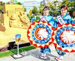 砂像の前で鳥取の魅力をＰＲする鳥取しゃんしゃん鈴の音大使の坂口さん（左）と吉尾さん
