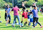 山岸さん（正面中央）と共に輪になってボールを蹴る親子連れら