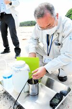 くみ上げた海水の水質を測定する県保健事業団の職員＝１５日、湯梨浜町橋津のハワイ海水浴場
