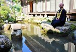 庭の池に設置された戦国時代初頭の水鉢と千代西尾住職＝２９日、鳥取市福井の龍福寺