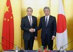 　会談前、握手する中国の王毅外相（左）と岩屋外相＝２２日午後、東京都千代田区（代表撮影）