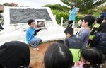 米軍の上陸地点になったことを伝えるモニュメントの前で説明を聞く小学生ら＝１日午後、沖縄県北谷町