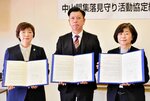 協定書を手にする久我支店長（中央）ら関係者＝１４日、米子市役所