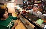 　立ち飲み屋を切り盛りする長男スンタラ（右）と話すピンマチャン＝神奈川県大和市
