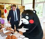 　フランスのセトン駐日大使（左）からフランスの朝食について説明を受ける「くまモン」＝２日午前、東京都港区