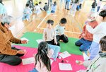 大人たちに教わりながら昔遊びを楽しむ児童たち