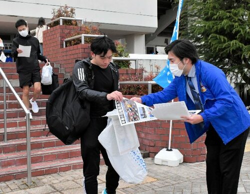 熱気に包まれた大会の様子を伝える号外を受け取るランナーや関係者＝１７日、鳥取市のヤマタスポーツパーク陸上競技場