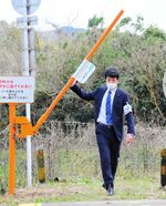 遮断棒「踏切ゲート―Ｌｉｔｅ」を持ち上げて横断するＪＲ西職員＝２０２４年３月18日、鳥取県湯梨浜町の山陰線・下山踏切