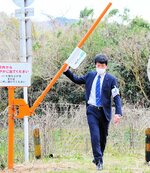 「踏切ゲート－Ｌｉｔｅ」の遮断棒を持ち上げて踏切を横断するＪＲ西日本の職員＝１８日、湯梨浜町北福のＪＲ山陰線下山踏切