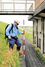 専用のポールを使って護岸を点検する職員