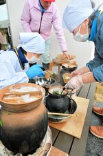弥生土器のレプリカで七草がゆを作るスタッフ